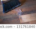 Close-up of a broom sweeping dust and dirt on a wooden floor 131761840