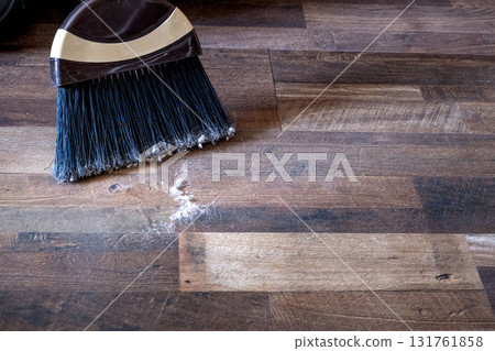 Close-up of a broom sweeping dust and dirt on a wooden floor 131761858