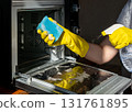 A person wearing yellow rubber gloves is cleaning an oven 131761895