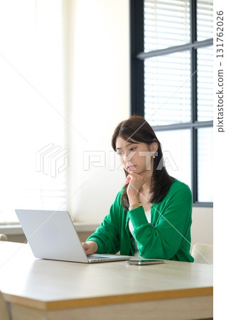 A woman in office casual clothes working on a laptop A woman in office casual clothes working on a laptop 131762026
