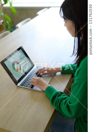 A woman in office casual clothes working on a laptop 131762030