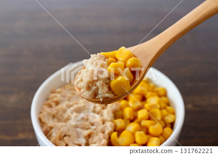 Tuna mayonnaise corn scooped with a wooden spoon on a table background 131762221
