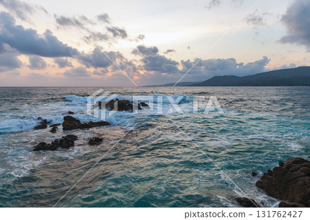 Black rocks are in shallow water at sunset. Coastal landscape of Propriano, Corsica 131762427