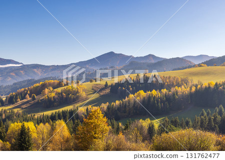 Scenic landscape view of an autumn mountain valley with lush forests rolling hills and clear blue sky. Northwest of Slovakia, Europe. Scenic landscape view of an autumn mountain valley with lush forests rolling hills and clear blue sky. Northwest of Slovakia, Europe. 131762477