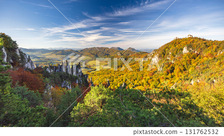 Scenic autumn landscape featuring rocky outcrops, vibrant foliage, rolling hills, and a wispy blue sky, perfect for exploration. The Sulov Rocks, national nature reserve in Slovakia, Europe. Scenic autumn landscape featuring rocky outcrops, vibrant foliage, rolling hills, and a wispy blue sky, perfect for exploration. The Sulov Rocks, national nature reserve in Slovakia, Europe. 131762532