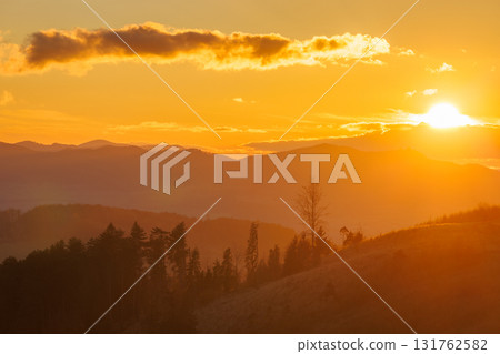 Golden hour lights up the mountains, with a sky ablaze in warm hues during a breathtaking sunrise. 131762582