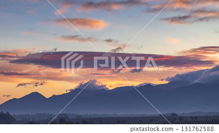 Mountain silhouettes under a painted sky, sunrise's soft hues ignite the horizon. Nature's spectacle unfolds. Mountain silhouettes under a painted sky, sunrise's soft hues ignite the horizon. Nature's spectacle unfolds. 131762588
