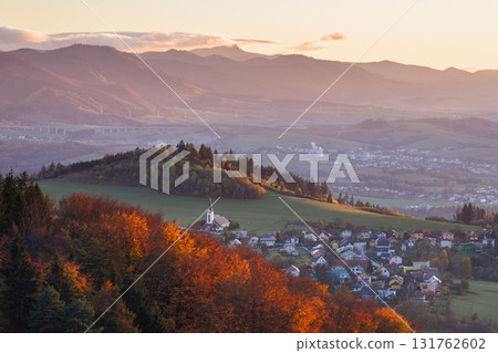 Autumnal Village: A serene European village nestled amidst mountains, bathed in golden light during fall. The Mala Fatra national park in Slovakia at background, Europe. 131762602