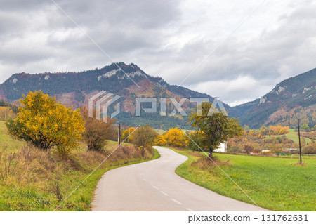 Winding Road Through Autumn Landscape: Trees and Mountains Under a Cloudy Sky, Serene Nature Scenery The Liptov region in Slovakia, Europe. Winding Road Through Autumn Landscape: Trees and Mountains Under a Cloudy Sky, Serene Nature Scenery The Liptov region in Slovakia, Europe. 131762631