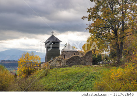 Wooden church in The Liptovska Anna village in northern Slovakia, Europe. Scenic view of a historic church ruin with a wooden tower under a cloudy sky in a rural setting. Wooden church in The Liptovska Anna village in northern Slovakia, Europe. Scenic view of a historic church ruin with a wooden tower under a cloudy sky in a rural setting. 131762646