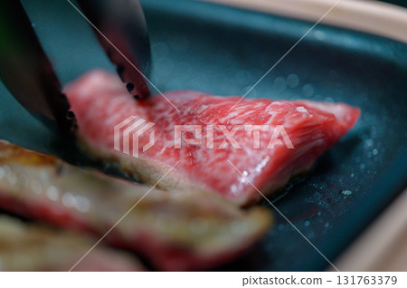 Hands grilling meat 131763379