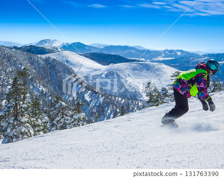 單板滑雪者轉彎時踢起的雪和冬季山脈的全景（群馬縣澀峠） 131763390