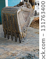 A close-up vertical shot of a steel excavator bucket lowered onto paving slabs at a construction site at the end of a work shift. Attachments of construction specialized equipment 131763400