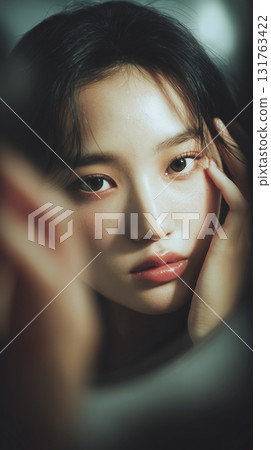 Captivating portrait of a Korean woman reflecting in a mirror during a soft-lit setting Captivating portrait of a Korean woman reflecting in a mirror during a soft-lit setting 131763422