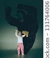 Bright poster. Little boy raising hands in surprise before huge gorilla shadow on green wall 131764006