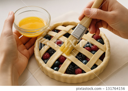 Close up of hands glazing unbaked lattice berry pie with egg wash on parchment paper for homemade dessert preparation, AI Generative 131764156