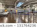 An interior, wide-angle view of a utilitarian and sparsely populated airport or ferry terminal waiting area.  131764236