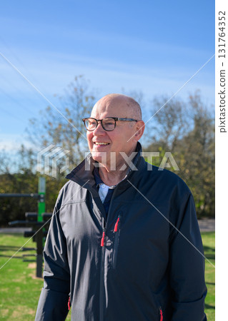 Smiling senior man in sportswear exercising outdoors at park fitness area 131764352