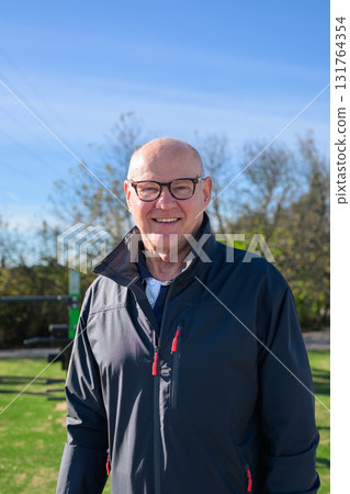 Smiling senior man in sportswear exercising outdoors at park fitness area 131764354