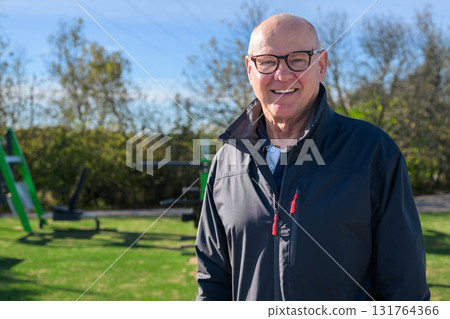 Smiling senior man in sportswear exercising outdoors at park fitness area 131764366