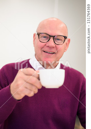 Portrait of a senior man with a cup of coffee smiling at the camera 131764369