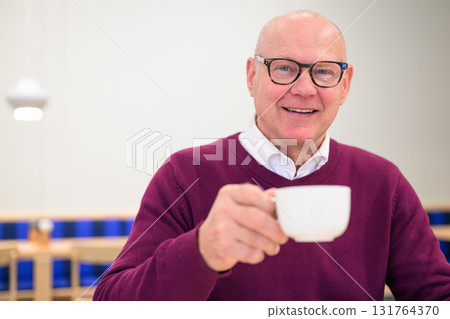 Portrait of a smiling senior man holding a cup of coffee Portrait of a smiling senior man holding a cup of coffee 131764370