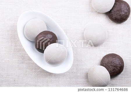 Peppernuts, Christmas cookies in an elongated oval white bowl. Popular German holiday treat, small spice cookies similar to gingerbread. Pastry coated with sugar glaze or dark chocolate. Peppernuts, Christmas cookies in an elongated oval white bowl. Popular German holiday treat, small spice cookies similar to gingerbread. Pastry coated with sugar glaze or dark chocolate. 131764686