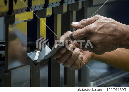 Close up the bending machine operator hold the sheet metal parts. Close up the bending machine operator hold the sheet metal parts. 131764895