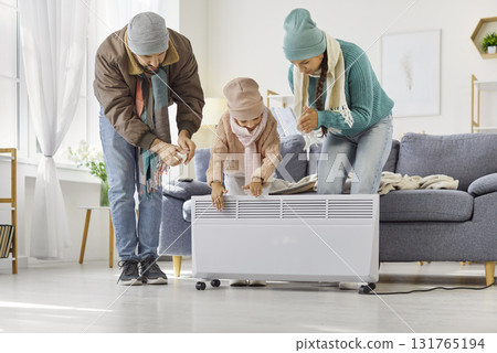 Family adjusting portable electric heater at home to stay warm during winter Family adjusting portable electric heater at home to stay warm during winter 131765194