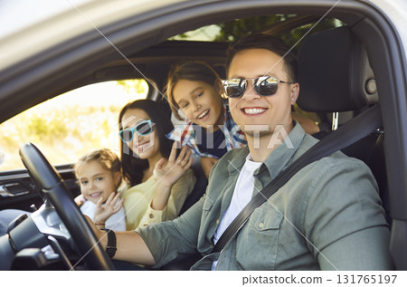 Smiling family driving car on road trip, happy parents with children enjoying ride 131765197