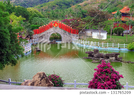 A traditional stone bridge with red lanterns in Nianshan Park, Sanya, Hainan, China. 131765209
