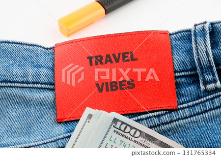 Denim jeans with a red patch displaying Travel Vibes, a stack of United States dollars, and a highlighter suggest financial readiness for travel planning Denim jeans with a red patch displaying Travel Vibes, a stack of United States dollars, and a highlighter suggest financial readiness for travel planning 131765334