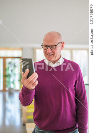 Portrait of senior man using mobile phone in living room at home Portrait of senior man using mobile phone in living room at home 131766079