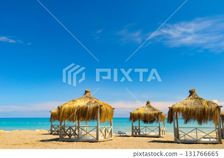 Thatched Beach Cabanas Under a Vibrant Blue Sky 131766665