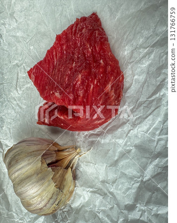 Raw beef cuts with garlic on crumpled parchment, top view cooking ingredients 131766759