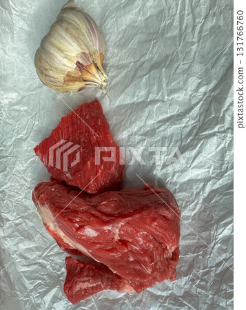 Raw beef cuts with garlic on crumpled parchment, top view cooking ingredients 131766760