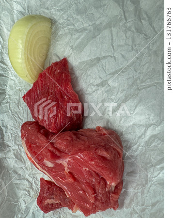 Raw beef cuts with onion slice on white parchment paper - fresh red meat food background, culinary ingredient closeup 131766763