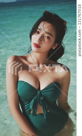 Model enjoying a sunny day in the ocean wearing a stylish green swimsuit while standing in the clear water Model enjoying a sunny day in the ocean wearing a stylish green swimsuit while standing in the clear water 131767018