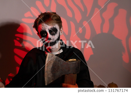 The model is holding an axe and posing for the camera For Halloween party. The model is holding an axe and posing for the camera For Halloween party. 131767174