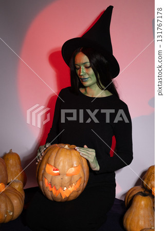 Woman holding pumpkin,standing in front of a rustic barn door with autumn leaves 131767178
