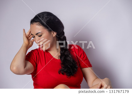 woman is holding her head with one hand and appears to be in discomfort or pain 131767179