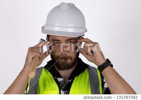 Man in hard hat and safety vest operating heavy machinery on construction site Man in hard hat and safety vest operating heavy machinery on construction site 131767362