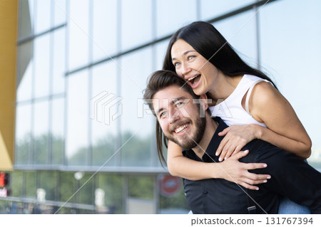 A man is giving a woman a piggyback ride while they both laugh and smile 131767394