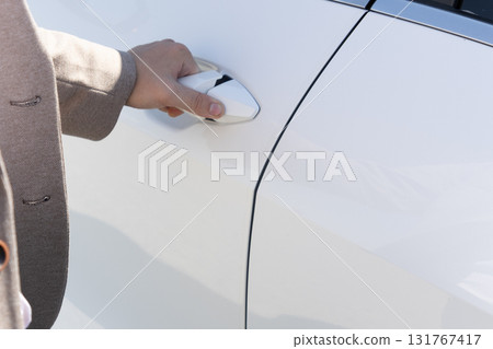 Person opening car door in a parking lot.Bright sunlight shines 131767417