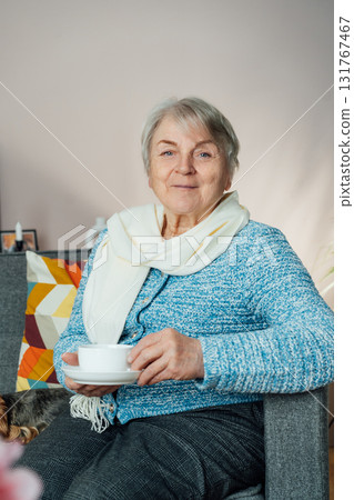 Smiling mature woman holding cup of tea, relaxing at home, positive senior female sitting on couch in modern living room looking satisfied feels good, older generation happy retired time enjoy life Smiling mature woman holding cup of tea, relaxing at home, positive senior female sitting on couch in modern living room looking satisfied feels good, older generation happy retired time enjoy life 131767467
