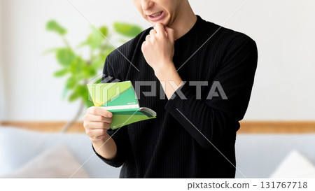 A man thinking while looking at his bankbook A man thinking while looking at his bankbook 131767718