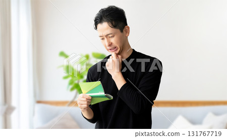 A man thinking while looking at his bankbook A man thinking while looking at his bankbook 131767719