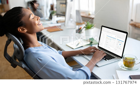 Young woman taking short break from work, practicing stress relief at her office desk with laptop computer, modern workplace wellness concept 131767974