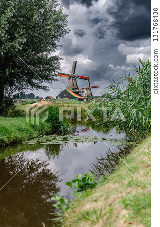 Scenic view of traditional Dutch windmills in Zaandam with changing skies, from calm daylight to approaching rain. Scenic view of traditional Dutch windmills in Zaandam with changing skies, from calm daylight to approaching rain. 131768430