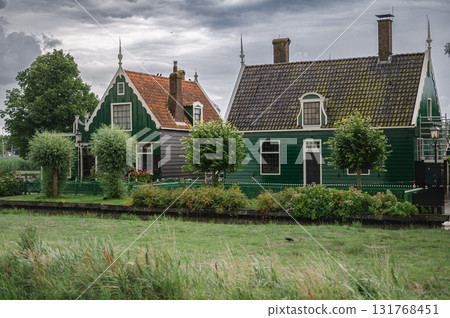 Scenic view of traditional Dutch windmills in Zaandam with changing skies, from calm daylight to approaching rain. 131768451